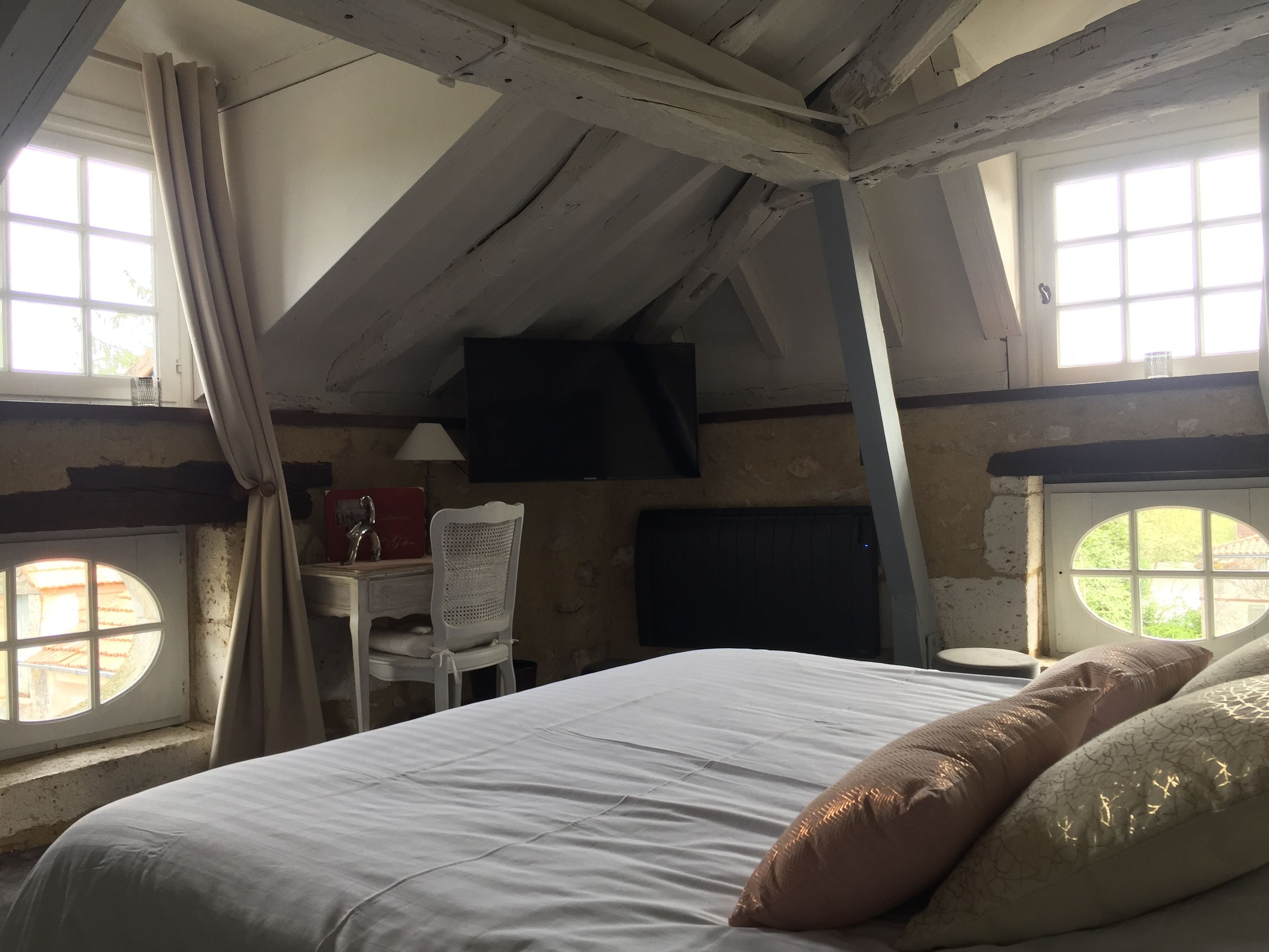 Een slaapkamer met een bed, een stoel, een bureau en een televisie.