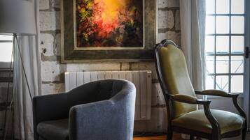Una habitación con chimenea, dos sillones, una lámpara de pie y un cuadro grande en la pared.