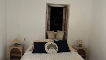 Quarto com cama, duas mesas de cabeceira, janela e vista para o exterior.
