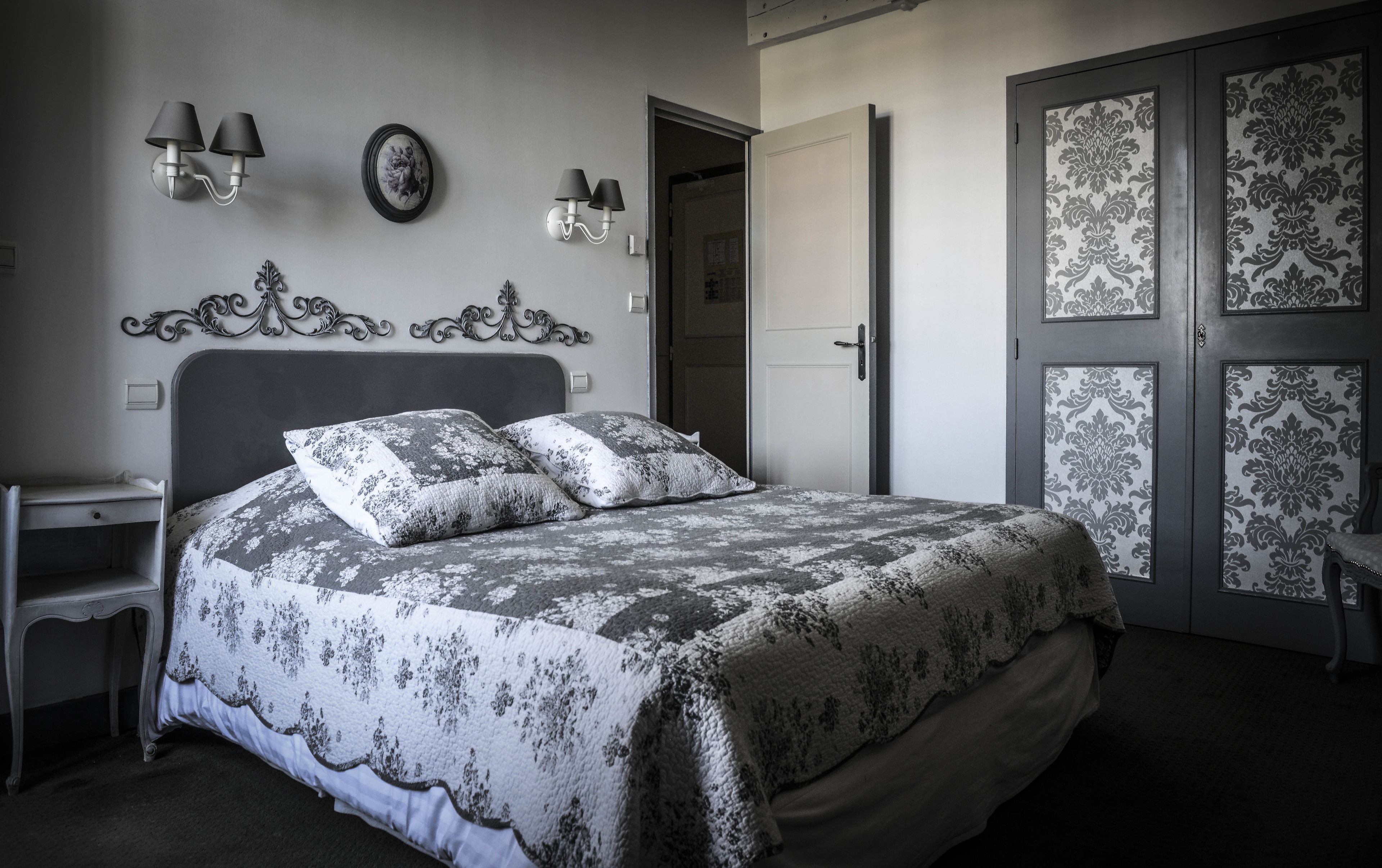 Un dormitorio con cama, mesitas de noche y una puerta con paneles de vidrio decorativo.