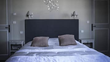 A bedroom with a large bed, two bedside lamps, a decorative wall piece, and a dark headboard.