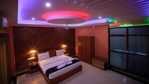 Une chambre d’hôtel moderne avec un lit en bois, un ventilateur de plafond et une grande fenêtre donnant sur un beau paysage.