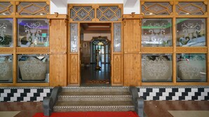 Une entrée imposante, avec de somptueuses portes en bois et des panneaux de verre aux motifs complexes.