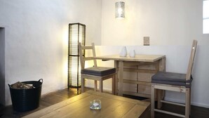 A small, cozy room with a wooden table, two chairs, a floor lamp, and a black trash bin. - Central Apartment for the Fringe (Edinburgh)