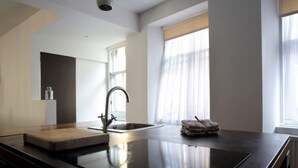 A modern kitchen with a central island, a stainless steel sink, and a window with sheer curtains. - Central Apartment for the Fringe (Edinburgh)
