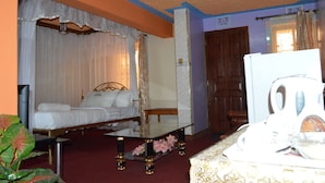 Une chambre d’hôtel comprenant un lit, une table de chevet, un miroir, une porte en bois et un coin cuisine.