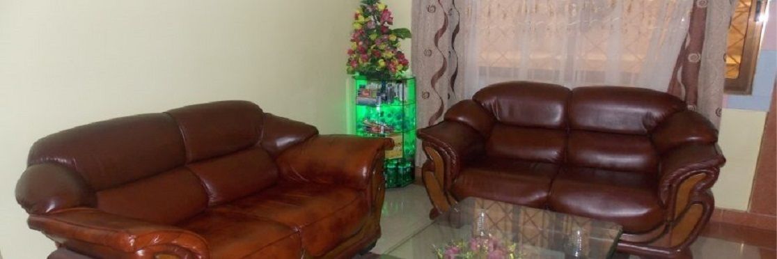 A brown leather sofa and a matching armchair in a room with a glass coffee table.