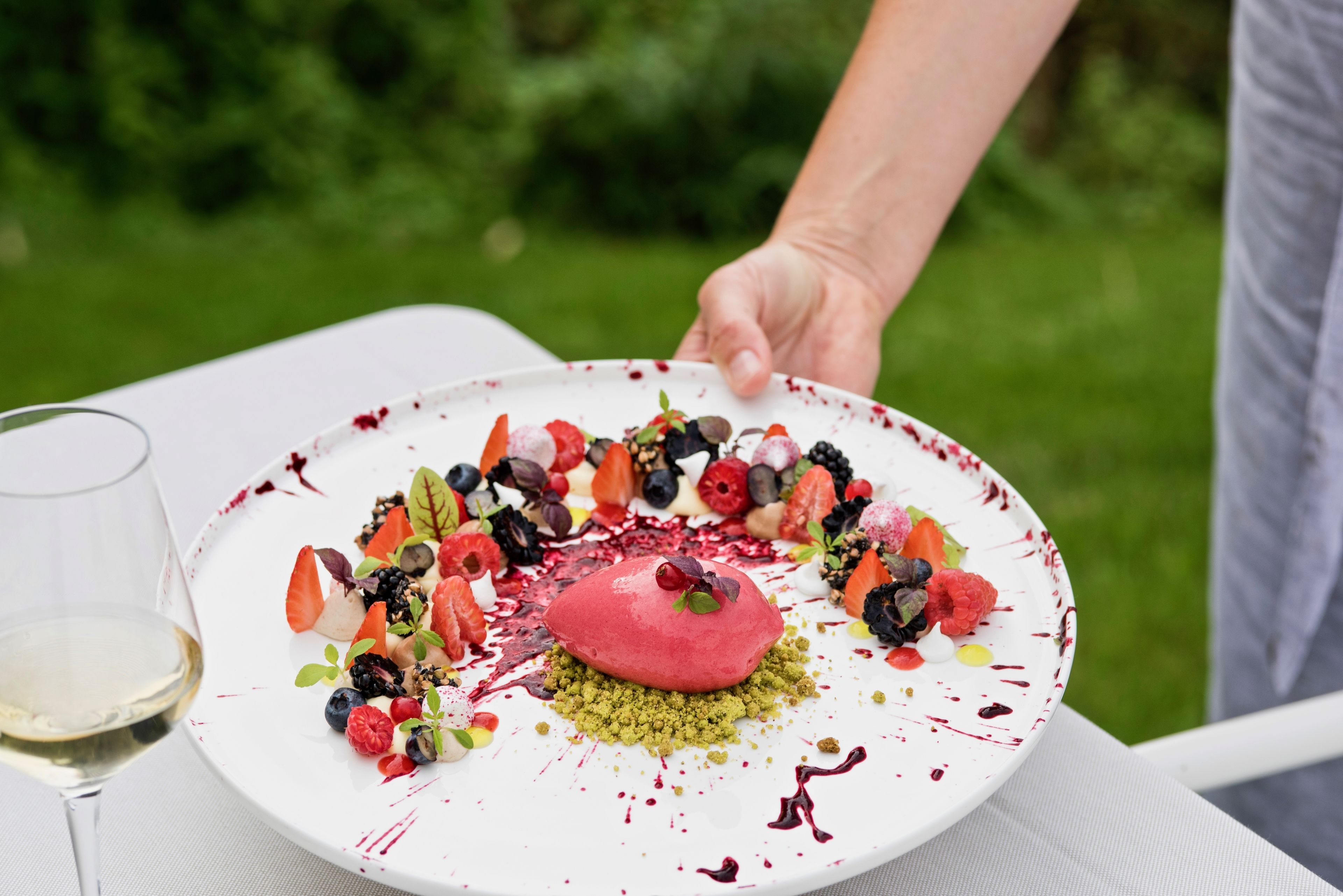 A dessert plate with various fruits and a scoop of ice cream, placed on a white table.