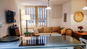 Una cucina moderna con isola centrale, tavolo da pranzo e divano in un soggiorno luminoso con ampie finestre.