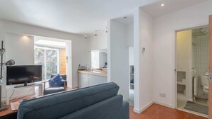 A modern living room with a flat-screen TV, a grey sofa, and a wooden coffee table.