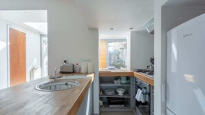 A modern kitchen with a wooden countertop, built-in oven, and a white refrigerator.