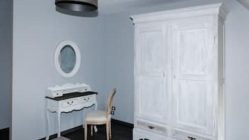Ett rum med en vit garderob, en sminkbord med spegel och en stol.