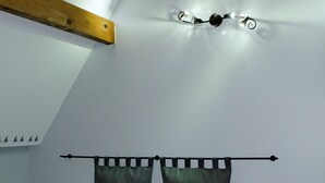 A bedroom with a sloped ceiling, a bed with a headboard, two bedside tables with lamps, and a wall-mounted light fixture. - La Ferme Aux Charmes (Solre-le-Château)
