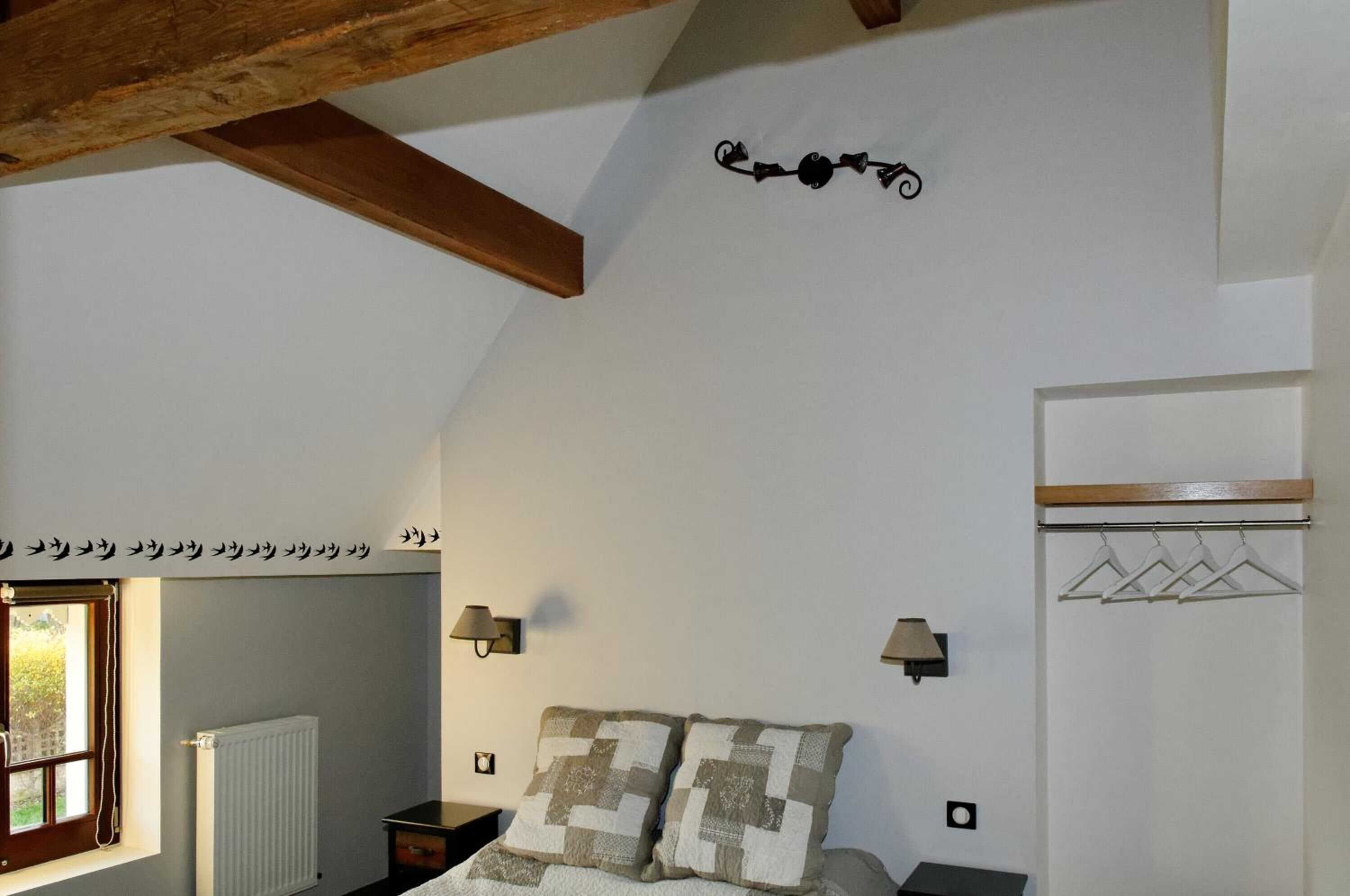 Een slaapkamer met een bed, een handdoekradiator, een raam en een kapstok.