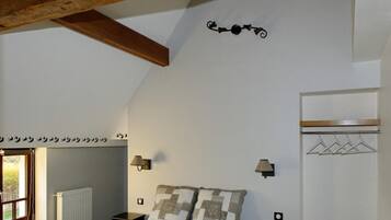 Een slaapkamer met een bed, een handdoekradiator, een raam en een kapstok.