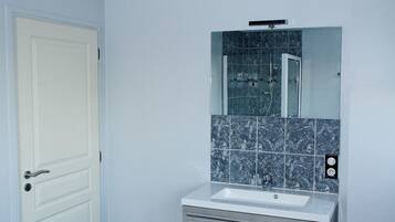 A bathroom with a white door, a sink with a mirror above it, and a tiled backsplash.