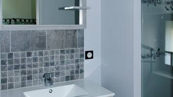 A bathroom with a white sink, a mirror, and a glass shower enclosure.