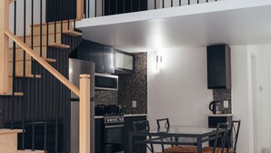 A modern kitchen with a dining area, a staircase, and a flat-screen TV. - Cjour Apartments (Montreal)