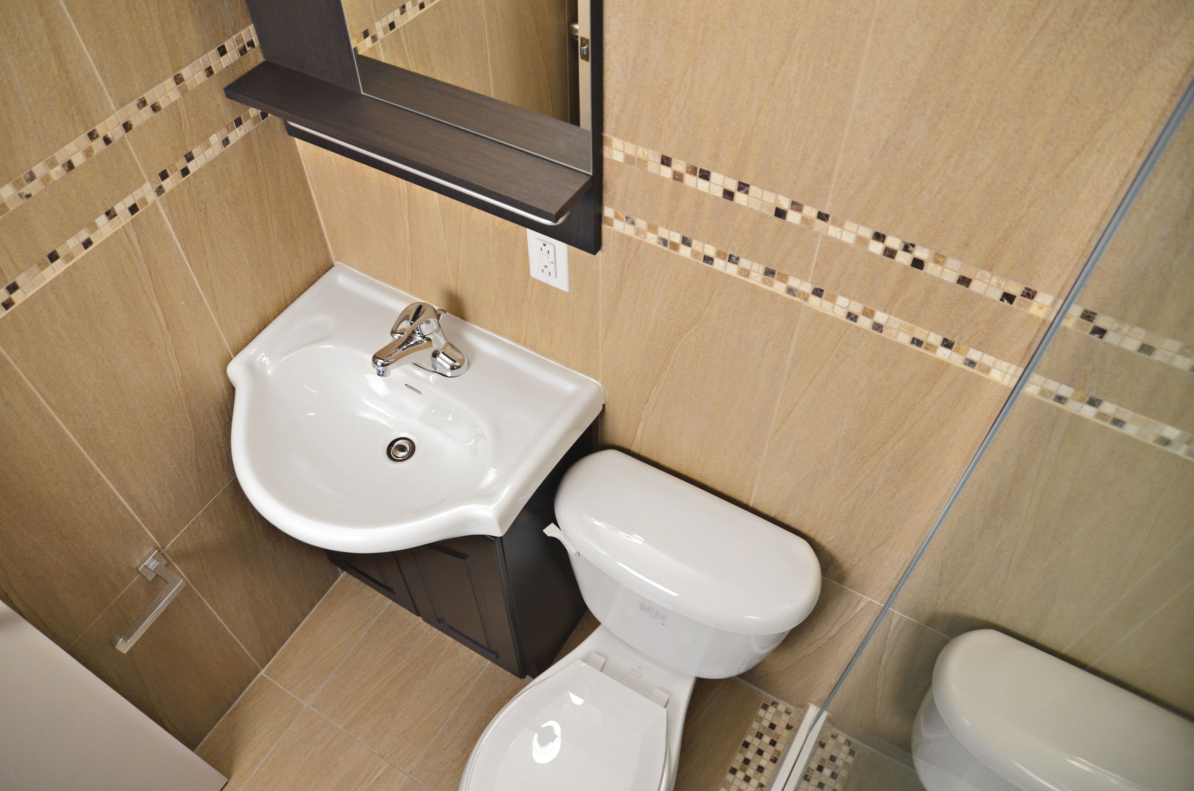 Ein Badezimmer mit einem weißen Waschbecken, einer Toilette und einem Spiegel über dem Waschbecken.