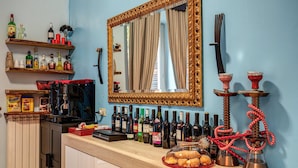Zona de bar con estantes de botellas de licores, una máquina de café y un narguilé.