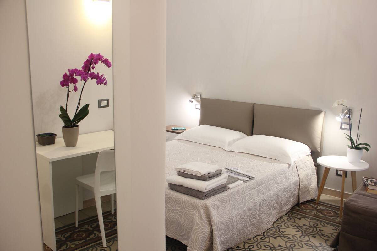 A hotel room with a bed, a desk, and a chair.