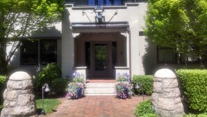 A two-story house with a front entrance, a stone pillar, and a brick pathway leading to the door. - Hilltop Inn (Newport)