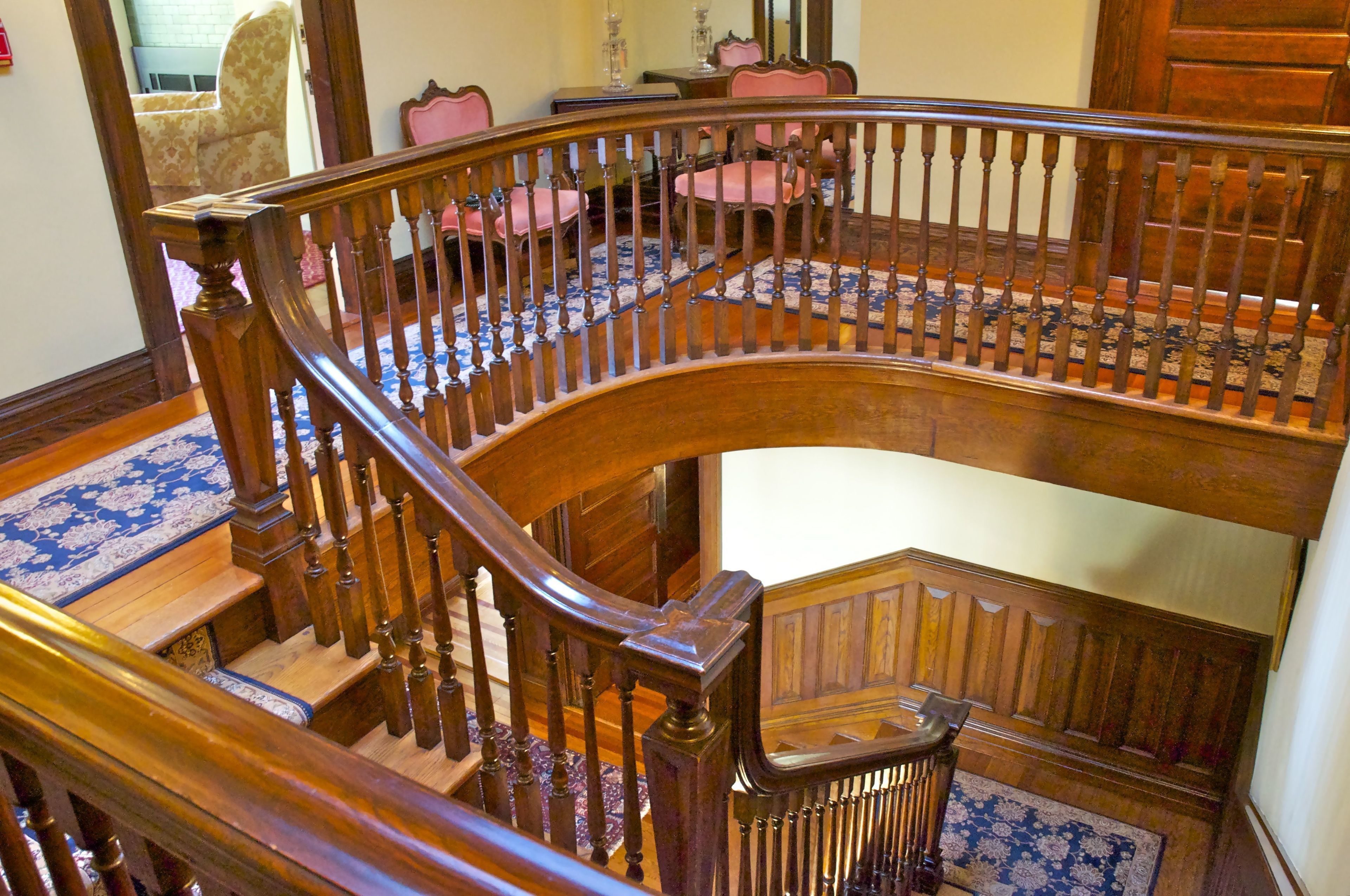 A grand wooden staircase with a curved design and a handrail, leading to an upper floor.