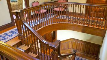A grand wooden staircase with a curved design and a handrail, leading to an upper floor.
