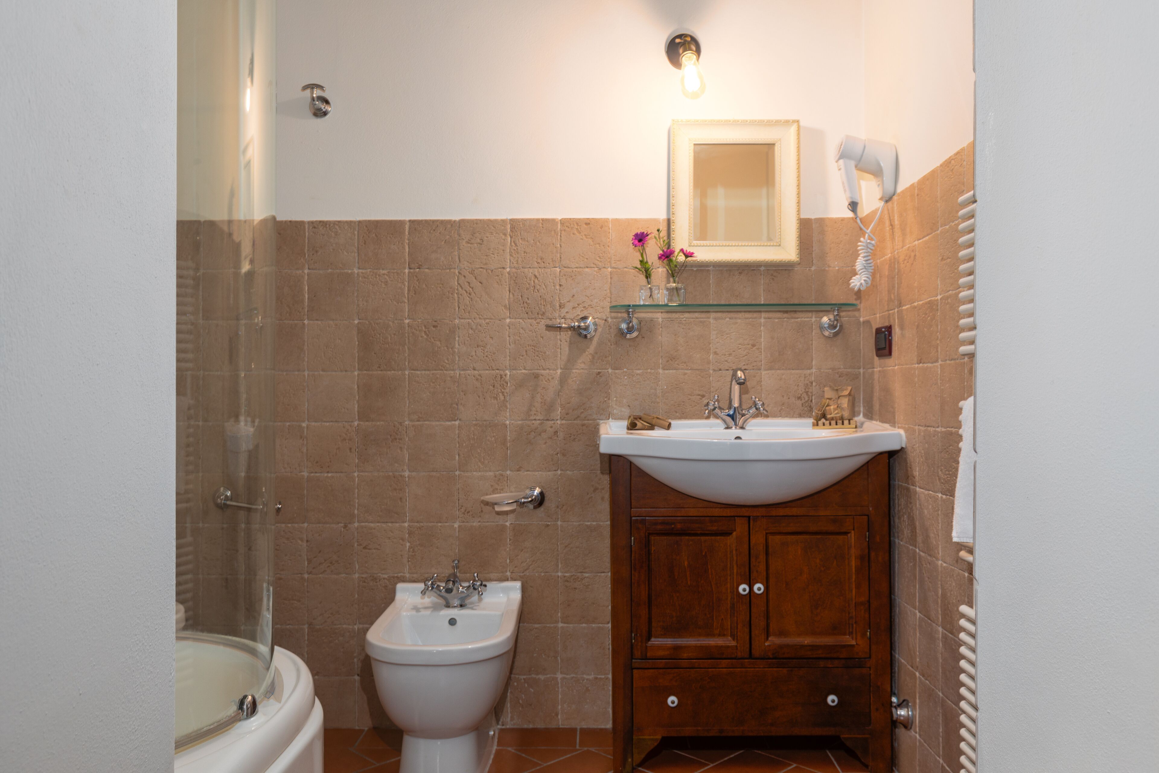 Un baño con bañera, bidé, lavamanos y espejo.