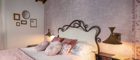 A bedroom with a bed, pillows, bedside lamps, a nightstand, and a telephone.