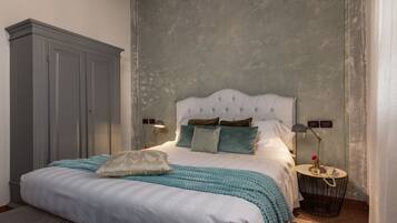 A bedroom with a large bed, a wardrobe, bedside lamps, and a small round table with a lamp.