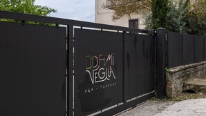 Een zwart metalen hek met de tekst 'DORMI VEGIA B&B - TUSCANY' erop.