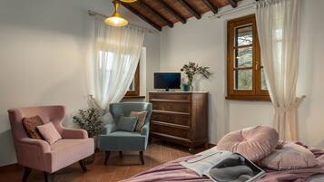 Une chambre confortable avec un lit, deux fauteuils, une commode et un téléviseur.