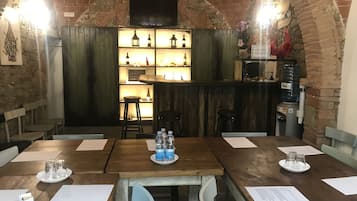 Un restaurante con paredes de ladrillo, mesas de madera y una zona de bar con estantes llenos de botellas y vasos.