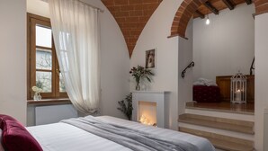 Een slaapkamer met een bed, een open haard en een trap naar een hoger gelegen verdieping.