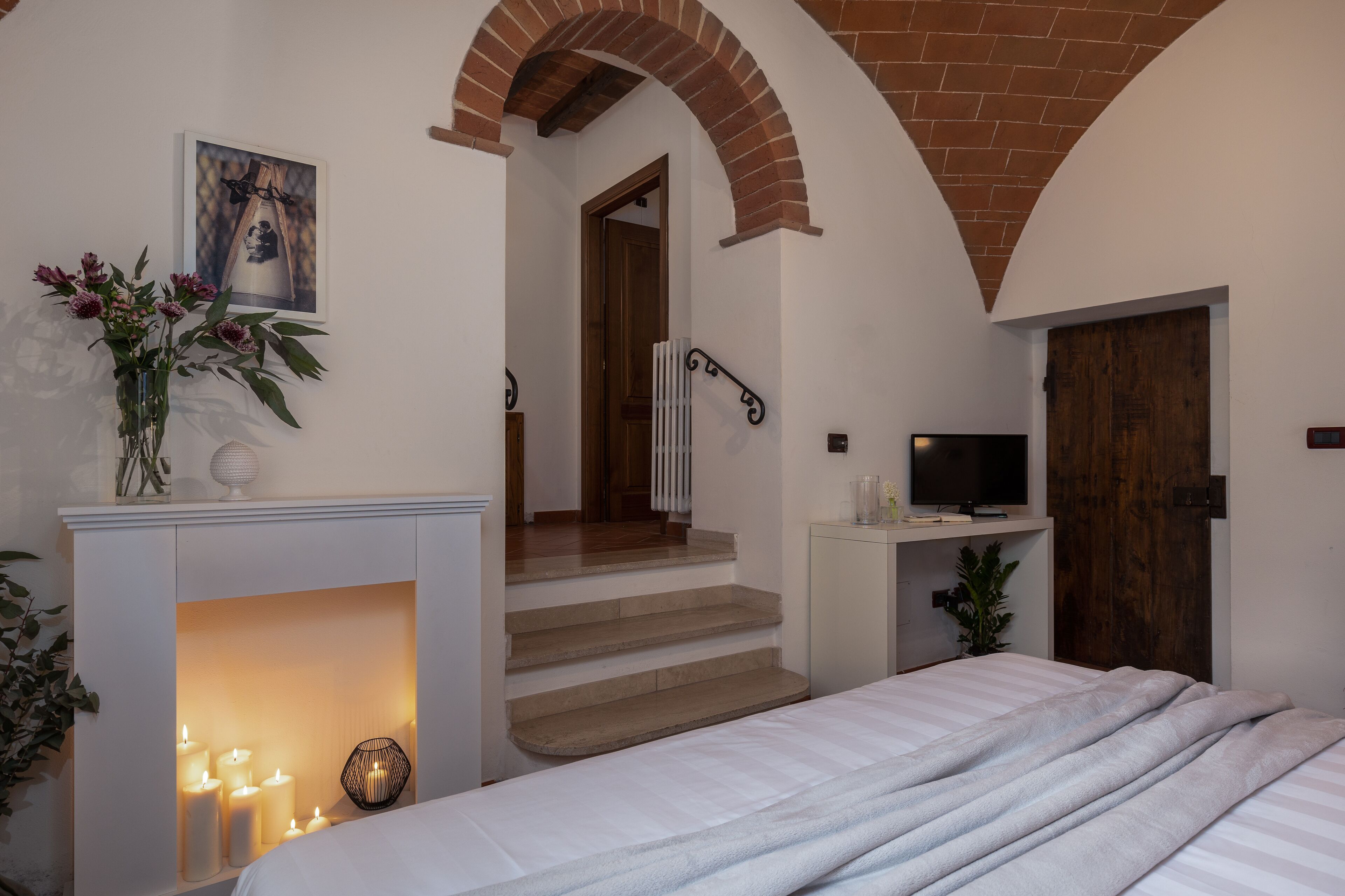 Een slaapkamer met een open haard, een televisie en een trap naar een andere kamer.
