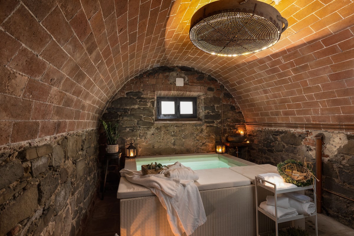 Un espace de bien-être doté d’une arche aux murs de pierre, d’un bain à remous et d’une petite fenêtre.