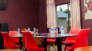 A conference room with a long table, red chairs, and water bottles on the table. - eMfuleni Lifestyle (Lobamba)