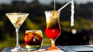 Three cocktails on a wooden table with a blurred outdoor background. - eMfuleni Lifestyle (Lobamba)