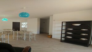 A spacious living area with a dining table and chairs, a black bookshelf, and a door leading to another room. - Villa Aurelio (Squillace)