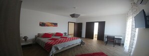 A bedroom with a bed, a desk, and a chair. There is a door leading to another room. - Villa Aurelio (Squillace)
