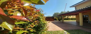 A covered outdoor area with a patio, a wooden structure in the background, and a clear sky. - Villa Aurelio (Squillace)
