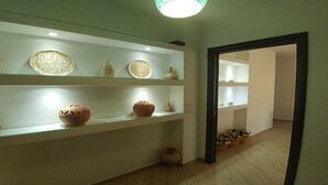 A hallway with glass display shelves containing pottery. - Villa Aurelio (Squillace)