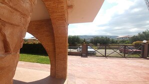 A stone wall and a brick archway leading to a paved area with a gated entrance. - Villa Aurelio (Squillace)