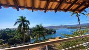 Vista panorámica desde un balcón con una imagen despejada de un lago, palmeras y montañas lejanas.