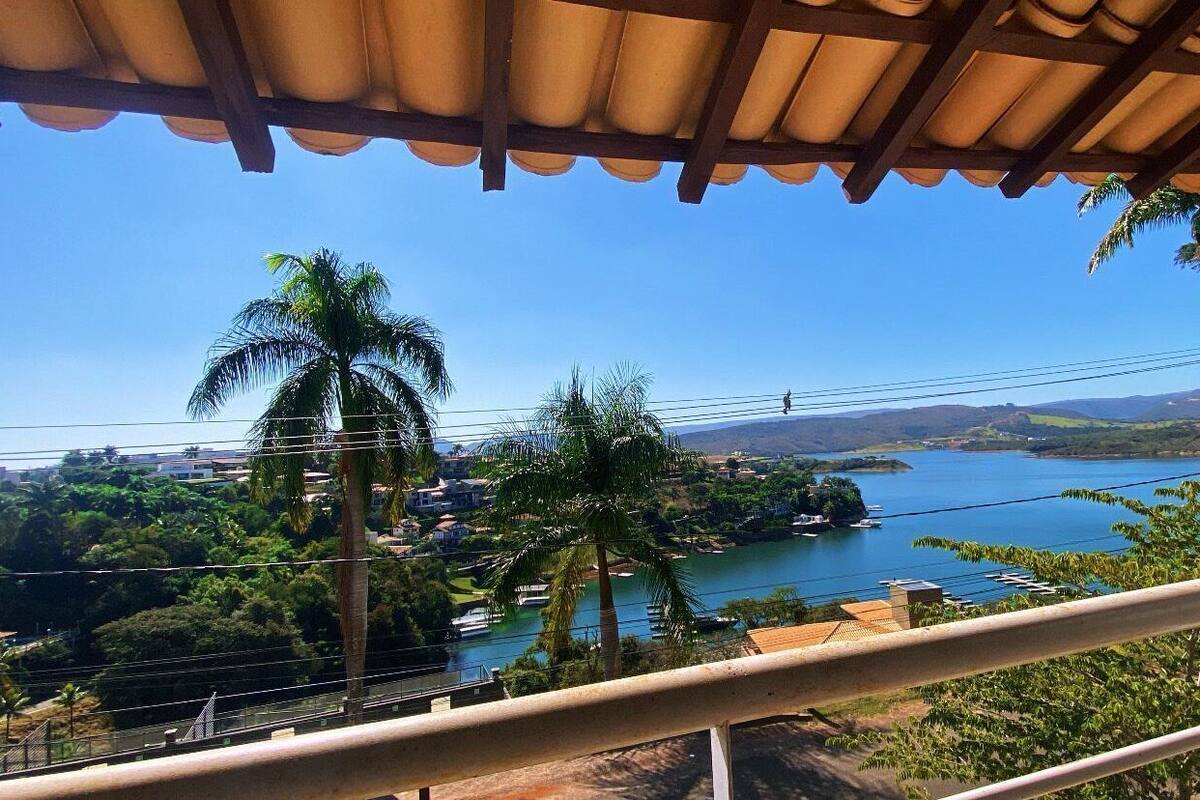 A scenic view from a balcony with a clear view of a lake, palm trees, and distant mountains.