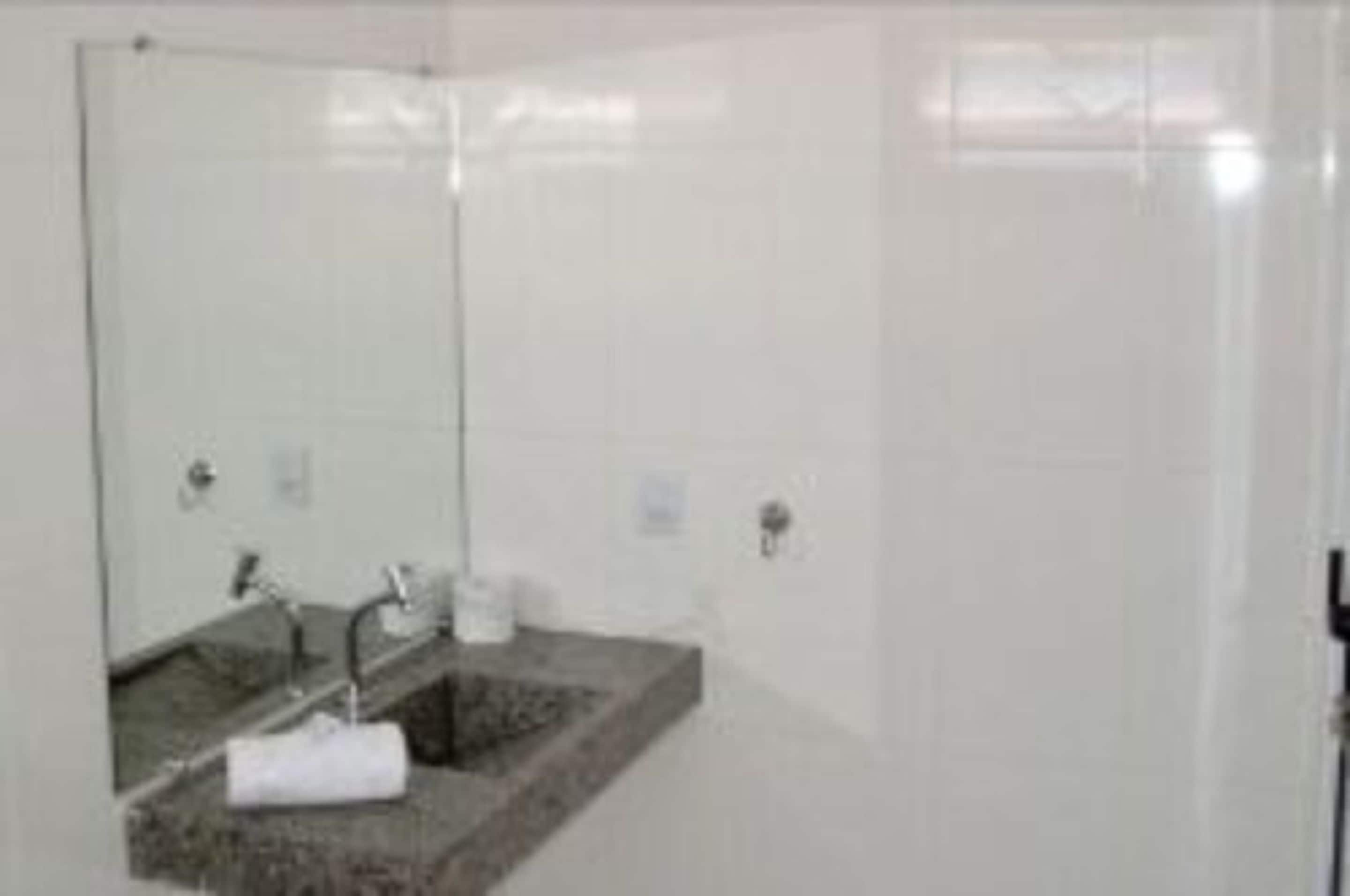 Un baño con cabina de ducha de vidrio, lavamanos de granito y un espejo.