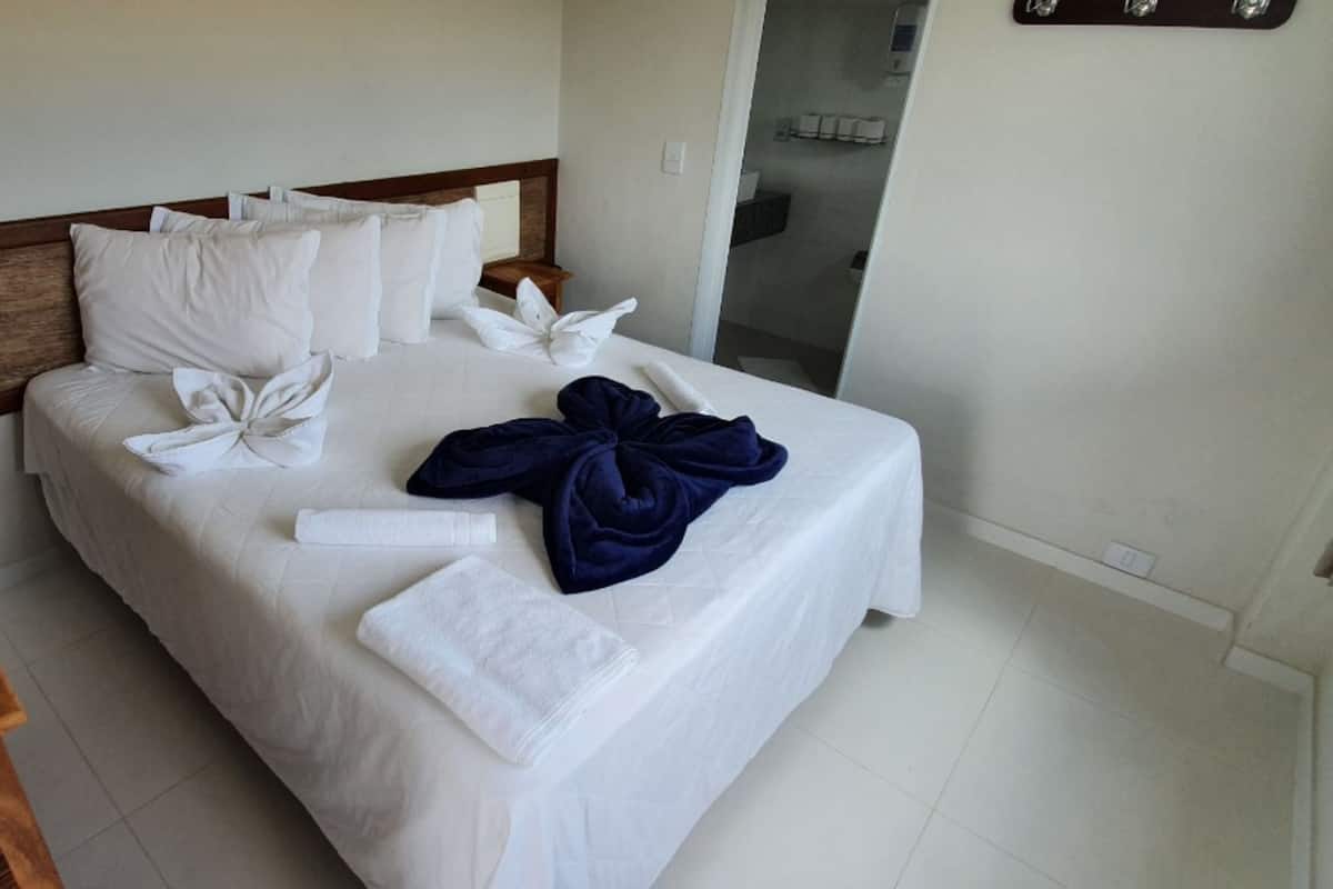 A neatly made bed with white linens, a wooden headboard, and towels arranged on the bed.