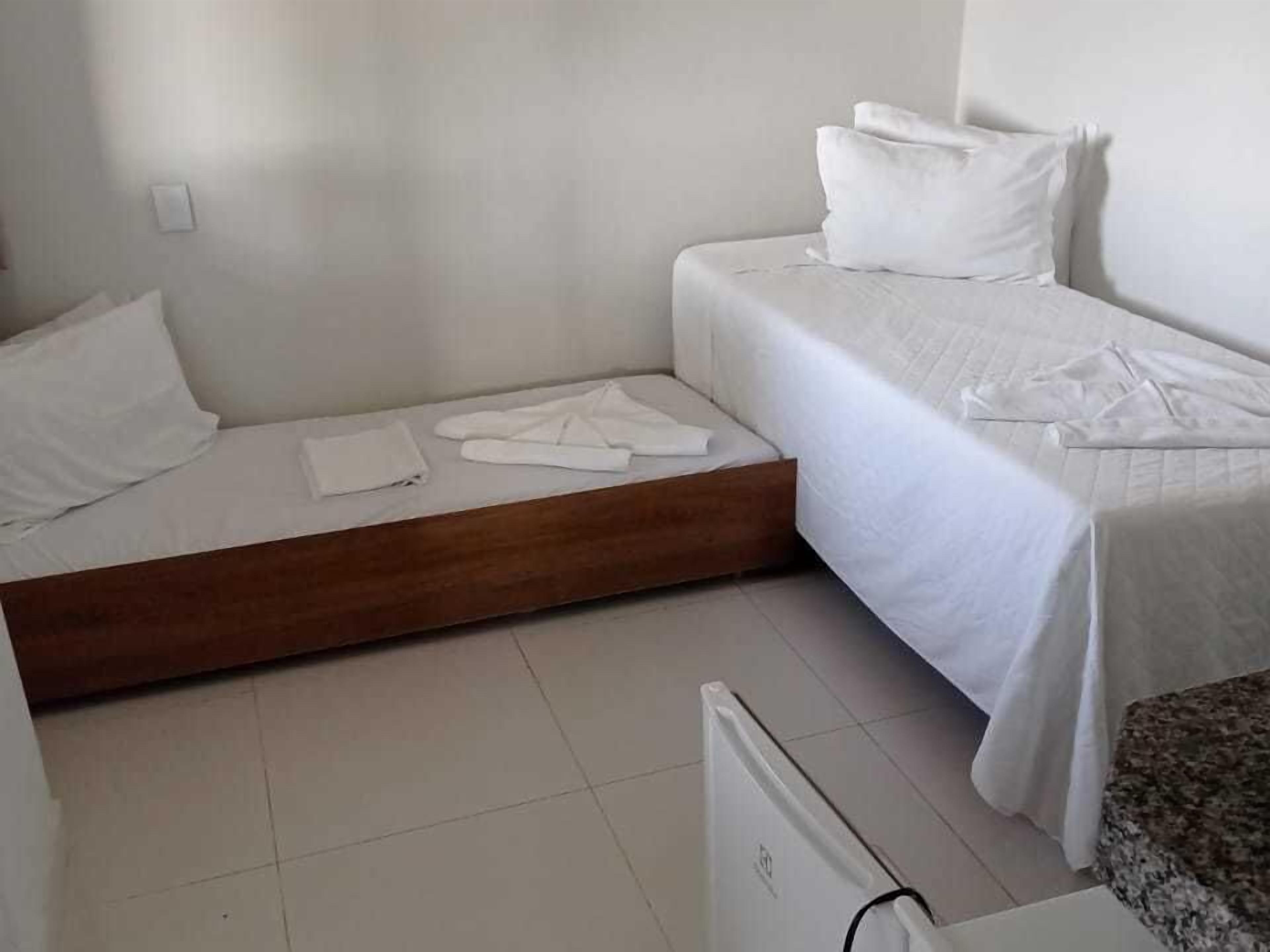 Una habitación pequeña y limpia con una cama, una plataforma de madera y un radiador.