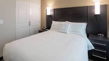 Ett hotellrum med en stor säng, två sängbord med lampor, en garderob och ett litet bord med en telefon och en väckarklocka.